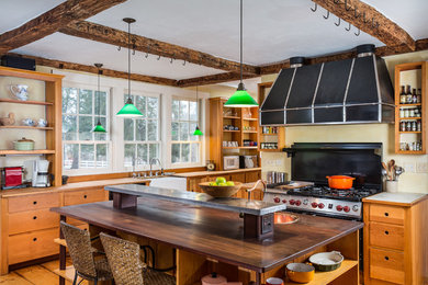 ブリッジポートにあるカントリー風のおしゃれなアイランドキッチン (エプロンフロントシンク、オープンシェルフ、中間色木目調キャビネット、木材カウンター、黒い調理設備) の写真