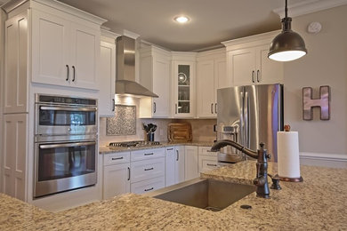Example of a mid-sized transitional l-shaped eat-in kitchen design in Other with a farmhouse sink, recessed-panel cabinets, white cabinets, granite countertops, stainless steel appliances and an island
