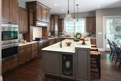 Inspiration for a mid-sized timeless u-shaped dark wood floor eat-in kitchen remodel in New York with stainless steel appliances, an island, an undermount sink, raised-panel cabinets, medium tone wood cabinets, quartzite countertops, beige backsplash and ceramic backsplash