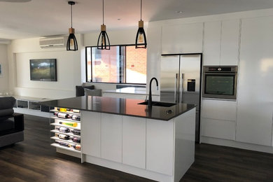 Modern inredning av ett mellanstort kök med öppen planlösning, med en undermonterad diskho, bänkskiva i koppar, stänkskydd i metallkakel, rostfria vitvaror, vinylgolv, en köksö och brunt golv
