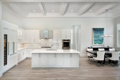 Example of a large trendy l-shaped light wood floor and gray floor open concept kitchen design in Miami with an undermount sink, shaker cabinets, white cabinets, quartzite countertops, gray backsplash, marble backsplash, stainless steel appliances and two islands