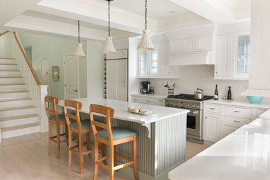 Example of a mid-sized classic l-shaped light wood floor eat-in kitchen design in Boston with recessed-panel cabinets, white cabinets, quartz countertops, white backsplash, paneled appliances and an island