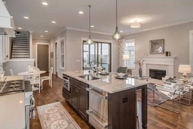 Large eclectic galley kitchen/diner in Nashville with an integrated sink, white cabinets, stainless steel appliances, medium hardwood flooring, an island and granite worktops.