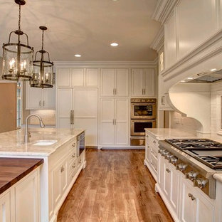 This is an example of a large shabby-chic style l-shaped open plan kitchen in Other with an undermount sink, beige cabinets, quartzite benchtops, white splashback, subway tile splashback, stainless steel appliances, with island, recessed-panel cabinets, medium hardwood floors and brown floor.