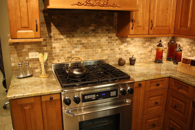 L-shaped kitchen photo in Chicago with medium tone wood cabinets, granite countertops, subway tile backsplash and stainless steel appliances