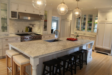 Enclosed kitchen - large transitional l-shaped light wood floor and brown floor enclosed kitchen idea in Boston with an undermount sink, recessed-panel cabinets, white cabinets, quartzite countertops, white backsplash, marble backsplash, stainless steel appliances, an island and white countertops