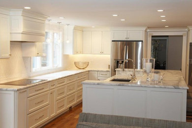 Inspiration for a large transitional l-shaped dark wood floor and brown floor eat-in kitchen remodel in Boston with an undermount sink, recessed-panel cabinets, white cabinets, quartzite countertops, white backsplash, ceramic backsplash, stainless steel appliances, an island and white countertops
