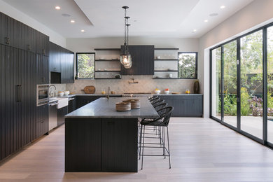 Large trendy l-shaped porcelain tile and beige floor open concept kitchen photo in Los Angeles with a farmhouse sink, dark wood cabinets, marble countertops, beige backsplash, ceramic backsplash, stainless steel appliances, an island, gray countertops and flat-panel cabinets
