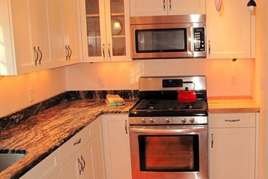 Example of a mid-sized medium tone wood floor kitchen design in Boston with a drop-in sink, recessed-panel cabinets, white cabinets, granite countertops and no island