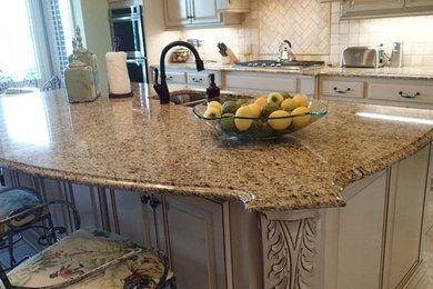 Eat-in kitchen - mid-sized traditional u-shaped ceramic tile eat-in kitchen idea in Other with a double-bowl sink, raised-panel cabinets, white cabinets, solid surface countertops, beige backsplash, stone slab backsplash, stainless steel appliances and an island