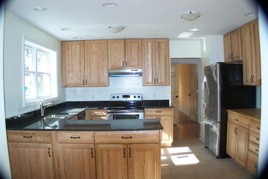 Inredning av ett klassiskt mellanstort kök, med en dubbel diskho, luckor med upphöjd panel, skåp i ljust trä, granitbänkskiva, vitt stänkskydd, rostfria vitvaror, travertin golv, en halv köksö och beiget golv