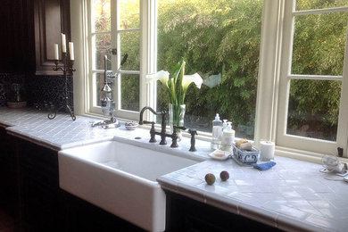 Mid-sized single-wall kitchen photo in San Francisco with a farmhouse sink, dark wood cabinets, tile countertops, blue backsplash and ceramic backsplash