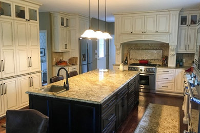 Eat-in kitchen - large transitional u-shaped medium tone wood floor and brown floor eat-in kitchen idea in Other with an undermount sink, recessed-panel cabinets, white cabinets, granite countertops, beige backsplash, travertine backsplash, stainless steel appliances and an island