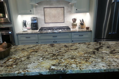 Klassisk inredning av ett kök, med vita skåp, granitbänkskiva och beige stänkskydd