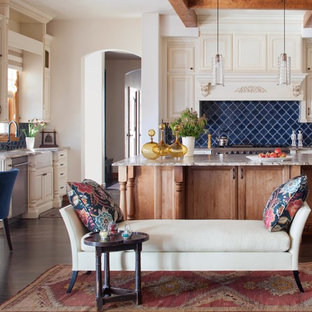 Photo of a mid-sized traditional l-shaped eat-in kitchen in Denver with a farmhouse sink, raised-panel cabinets, beige cabinets, blue splashback, granite benchtops, ceramic splashback, stainless steel appliances, dark hardwood floors and with island.