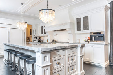 Inspiration for a large transitional u-shaped dark wood floor and brown floor eat-in kitchen remodel in Edmonton with a farmhouse sink, recessed-panel cabinets, white cabinets, marble countertops, white backsplash, subway tile backsplash, stainless steel appliances and an island