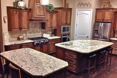 Example of a large dark wood floor kitchen design in Other with a double-bowl sink, medium tone wood cabinets, granite countertops, beige backsplash, ceramic backsplash, stainless steel appliances and two islands