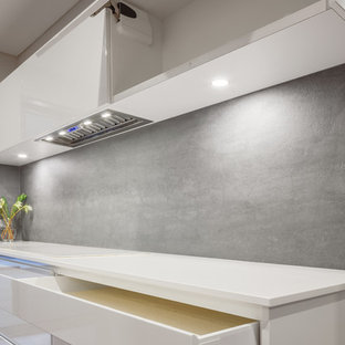 Imagen de cocina lineal, moderna, grande, cerrada, con fregadero encastrado, armarios con puertas mallorquinas, puertas de armario blancas, encimera de granito, salpicadero beige, salpicadero de azulejos de cemento, electrodomésticos negros, suelo de baldosas de terracota y una isla