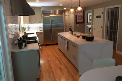 Ejemplo de cocina moderna con electrodomésticos de acero inoxidable, suelo de madera en tonos medios y una isla