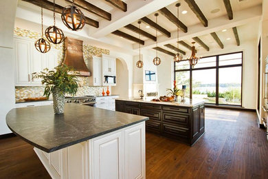 Eat-in kitchen - large transitional u-shaped medium tone wood floor eat-in kitchen idea in Austin with an integrated sink, raised-panel cabinets, white cabinets, soapstone countertops, multicolored backsplash, mosaic tile backsplash, stainless steel appliances and two islands