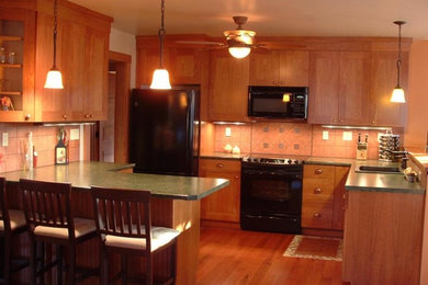 ニューヨークにあるおしゃれなキッチン (中間色木目調キャビネット、御影石カウンター、黒い調理設備、無垢フローリング) の写真