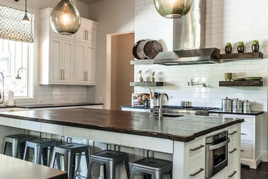 Enclosed kitchen - mid-sized modern u-shaped dark wood floor enclosed kitchen idea in Austin with a farmhouse sink, shaker cabinets, white cabinets, wood countertops, white backsplash, subway tile backsplash, stainless steel appliances and an island
