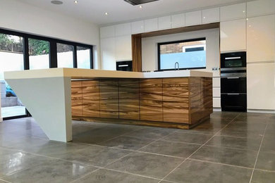 Photo of a large contemporary single-wall open plan kitchen in West Midlands with an integrated sink, glass-front cabinets, white cabinets, composite countertops, white splashback, window splashback, integrated appliances, porcelain flooring and an island.