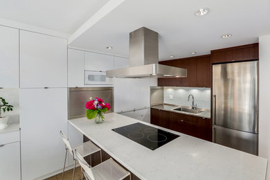Mid-sized minimalist u-shaped porcelain tile eat-in kitchen photo in Vancouver with a peninsula, flat-panel cabinets, white cabinets, quartz countertops, white backsplash, glass tile backsplash, stainless steel appliances and an integrated sink