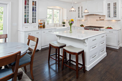 Inspiration for a mid-sized timeless l-shaped dark wood floor eat-in kitchen remodel in New York with a farmhouse sink, shaker cabinets, white cabinets, granite countertops, white backsplash, ceramic backsplash, stainless steel appliances and an island