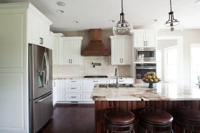 Eat-in kitchen - mid-sized traditional l-shaped medium tone wood floor and brown floor eat-in kitchen idea in Indianapolis with an undermount sink, raised-panel cabinets, white cabinets, granite countertops, beige backsplash, ceramic backsplash, stainless steel appliances, an island and multicolored countertops