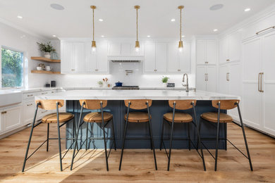 Example of a large country u-shaped medium tone wood floor and brown floor open concept kitchen design in San Francisco with a farmhouse sink, white cabinets, marble countertops, white backsplash, ceramic backsplash, paneled appliances, an island, white countertops and shaker cabinets