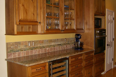 Example of a classic u-shaped medium tone wood floor eat-in kitchen design in Seattle with raised-panel cabinets, medium tone wood cabinets, granite countertops, multicolored backsplash, ceramic backsplash, stainless steel appliances and an island