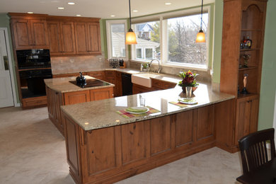 Example of a mid-sized classic u-shaped ceramic tile and beige floor eat-in kitchen design in Baltimore with a farmhouse sink, recessed-panel cabinets, dark wood cabinets, granite countertops, beige backsplash, ceramic backsplash, black appliances and an island