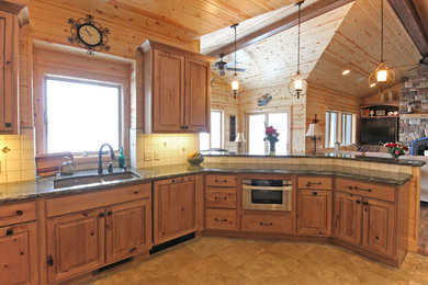 Foto på ett mellanstort lantligt u-kök, med en undermonterad diskho, luckor med upphöjd panel, skåp i ljust trä, granitbänkskiva, integrerade vitvaror och en halv köksö
