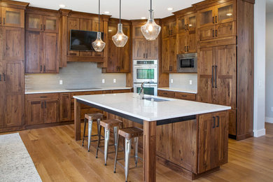 Inspiration for a large timeless l-shaped light wood floor open concept kitchen remodel in Other with an undermount sink, shaker cabinets, dark wood cabinets, quartz countertops, gray backsplash, glass tile backsplash, stainless steel appliances and an island