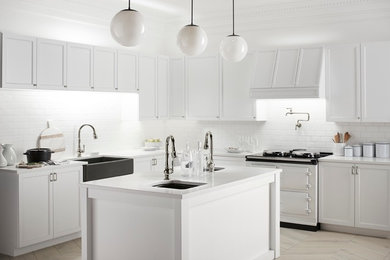 Photo of a contemporary l-shaped kitchen/diner in Boston with a belfast sink, recessed-panel cabinets, white cabinets, white splashback, ceramic splashback and an island.