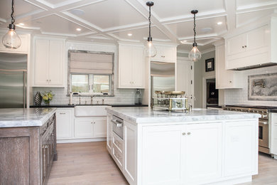 Large trendy u-shaped light wood floor and beige floor open concept kitchen photo in Orange County with two islands, a drop-in sink, shaker cabinets, white cabinets, marble countertops, multicolored backsplash, marble backsplash and stainless steel appliances