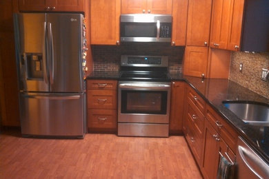 Kitchen photo in Columbus with no island, shaker cabinets, medium tone wood cabinets, granite countertops, stainless steel appliances and an undermount sink