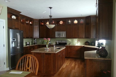 Example of a trendy u-shaped eat-in kitchen design in Cleveland with an undermount sink, recessed-panel cabinets, medium tone wood cabinets, granite countertops, beige backsplash and stainless steel appliances