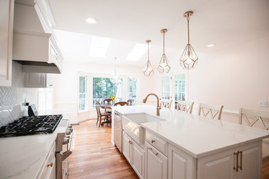 Photo of a large traditional l-shaped kitchen/diner in Richmond with a belfast sink, raised-panel cabinets, white cabinets, engineered stone countertops, stainless steel appliances, light hardwood flooring and an island.