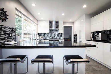 Diseño de cocinas en U moderno con armarios con paneles lisos, puertas de armario blancas y electrodomésticos de acero inoxidable