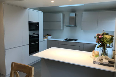 Design ideas for a medium sized contemporary u-shaped kitchen/diner in London with a double-bowl sink, flat-panel cabinets, grey cabinets, quartz worktops, stainless steel appliances, ceramic flooring, an island, grey floors and white worktops.