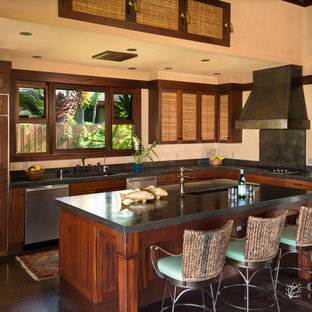 This is an example of a mid-sized tropical l-shaped open plan kitchen in Hawaii with an integrated sink, recessed-panel cabinets, medium wood cabinets, granite benchtops, black splashback, stone slab splashback, stainless steel appliances, concrete floors and with island.