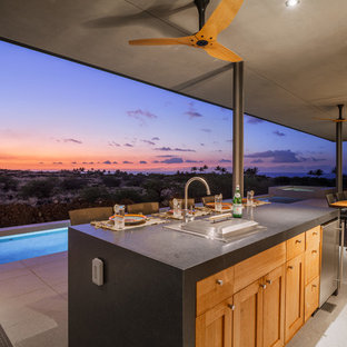 This is an example of a mid-sized tropical single-wall separate kitchen in Hawaii with an undermount sink, flat-panel cabinets, medium wood cabinets, granite benchtops, green splashback, glass tile splashback, stainless steel appliances, porcelain floors, with island and beige floor.