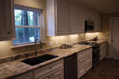 Example of a mid-sized classic galley ceramic tile eat-in kitchen design in Houston with an undermount sink, recessed-panel cabinets, white cabinets, granite countertops, stainless steel appliances and no island