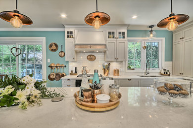 Inspiration for a mid-sized transitional l-shaped ceramic tile eat-in kitchen remodel in Montreal with an undermount sink, shaker cabinets, gray cabinets, quartz countertops, white backsplash, ceramic backsplash, black appliances and an island