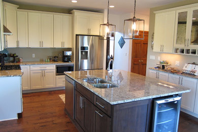 Inspiration for a large transitional u-shaped medium tone wood floor open concept kitchen remodel in Milwaukee with an undermount sink, shaker cabinets, beige cabinets, granite countertops and stainless steel appliances