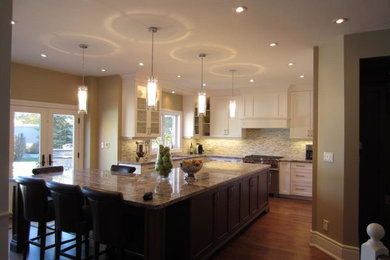 Inspiration for a timeless u-shaped medium tone wood floor eat-in kitchen remodel in Toronto with an undermount sink, recessed-panel cabinets, white cabinets, granite countertops, beige backsplash, stone tile backsplash, paneled appliances and an island