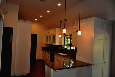 Photo of a medium sized classic l-shaped enclosed kitchen in Los Angeles with flat-panel cabinets, white cabinets, granite worktops, stone slab splashback, dark hardwood flooring, a breakfast bar and a single-bowl sink.