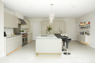 This is an example of a large contemporary enclosed kitchen in Hertfordshire with a double-bowl sink, flat-panel cabinets, quartz worktops, stainless steel appliances, ceramic flooring, an island, white floors, white worktops, beige cabinets and metallic splashback.